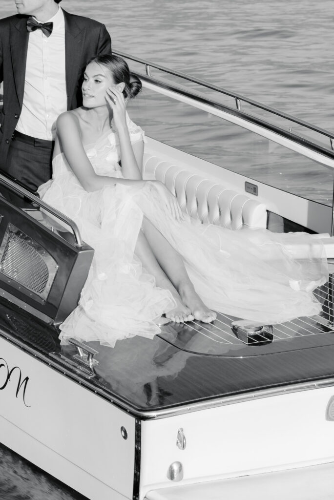 Bride and groom in wedding attire on a vintage cigarette boat at Lake Como
