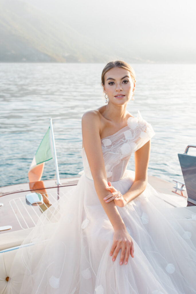 Bride in golden hour at a vintage cigarette boat on the lake by the dock of the Grand Hotel Tremezzo